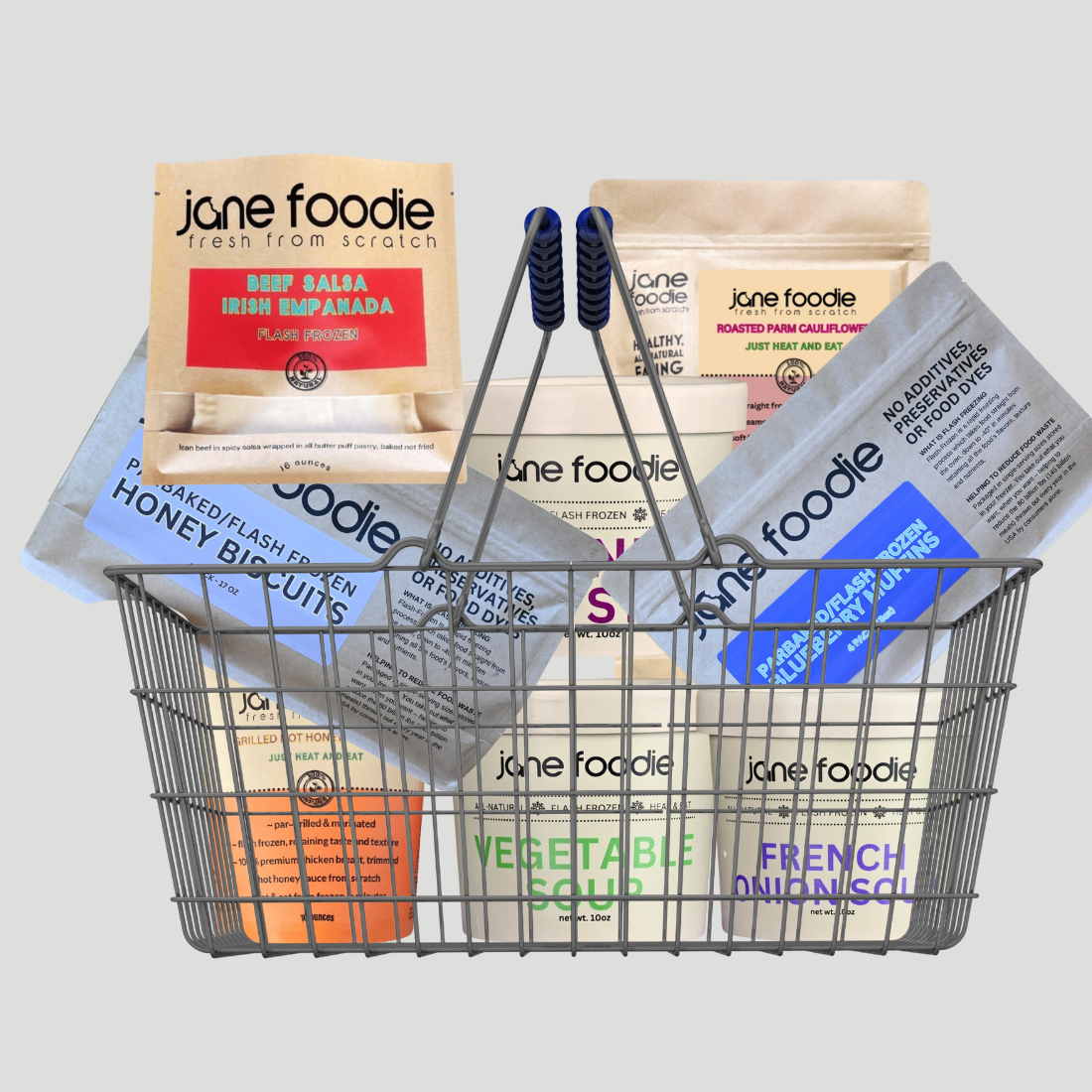 Metal shopping basket filled with various 'jane foodie' products on a light gray background