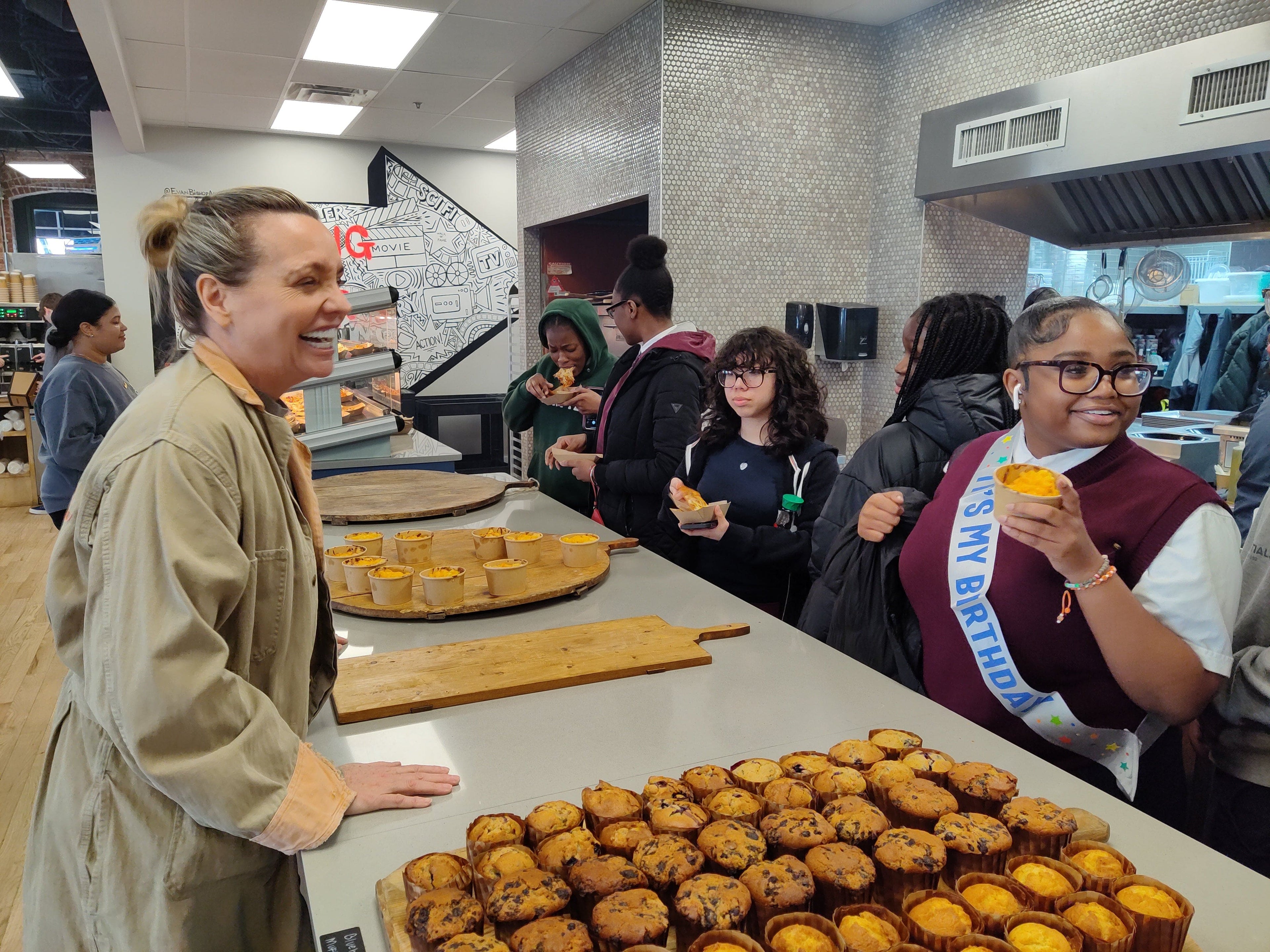 People gathered around a counter with baked goods in a casual indoor setting