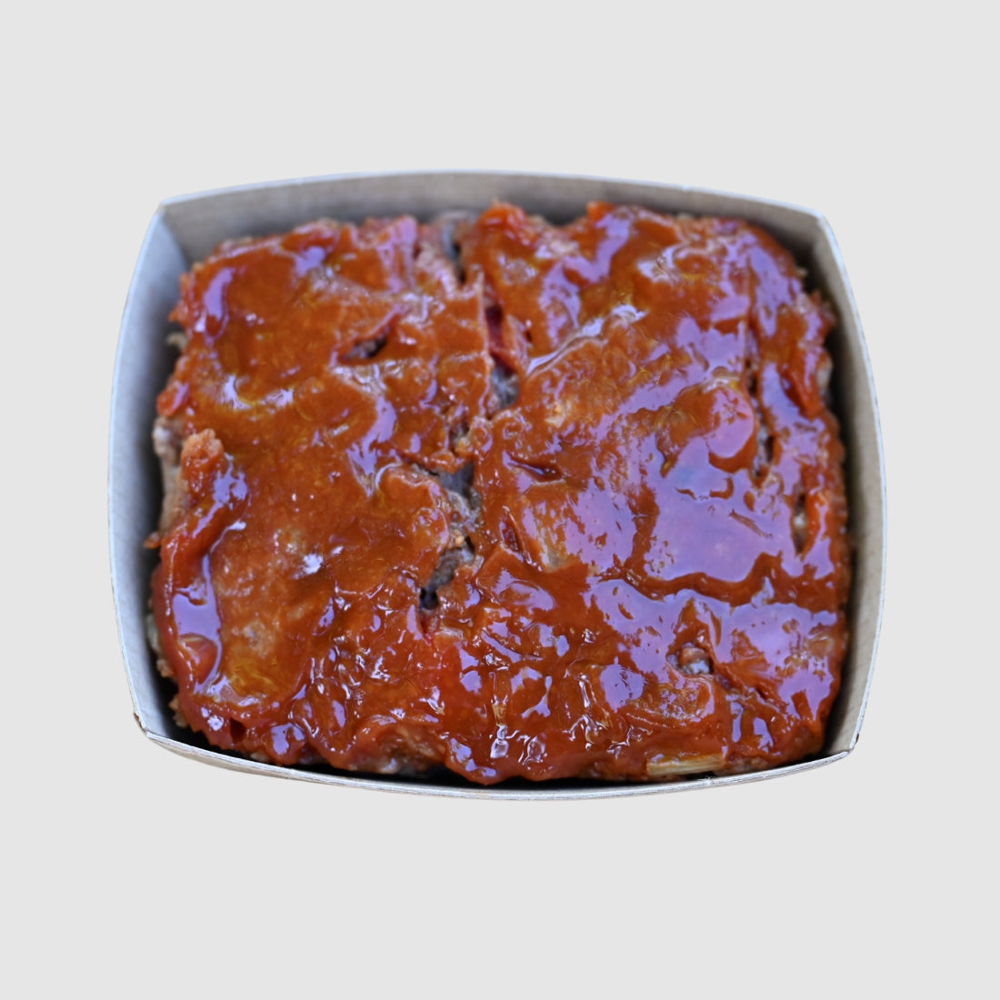 meatloaf with a ketchup glaze on a light gray background