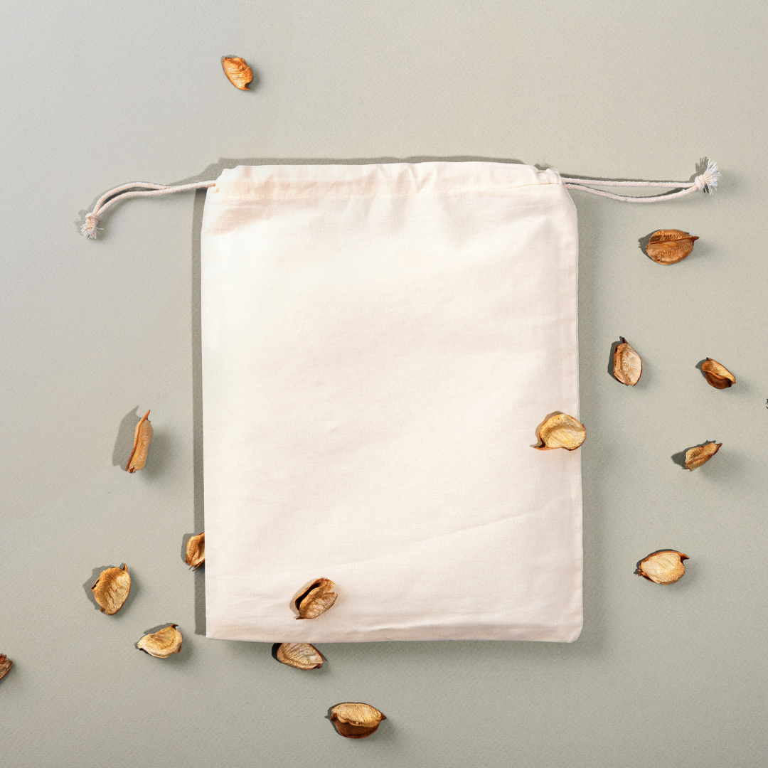 White drawstring bag on a light gray background with scattered wooden beads.