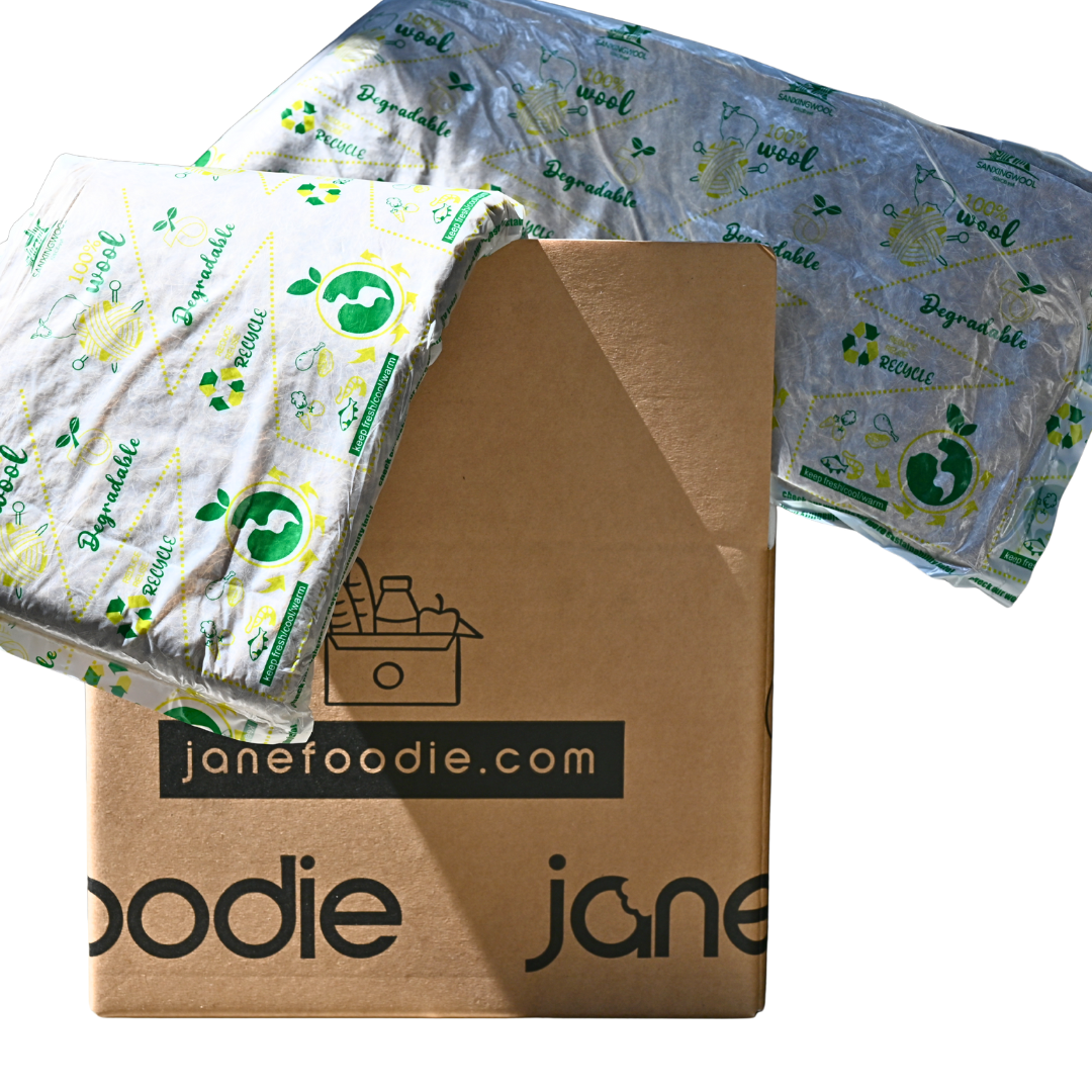 Cardboard box with 'janefoodie.com' branding, surrounded by eco-friendly food packaging.