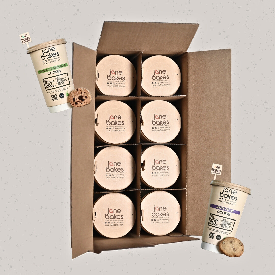 Jane Bakes cookie cups in eco-friendly cardboard case, with hazelnut and chocolate chip cookies displayed on light gray background.