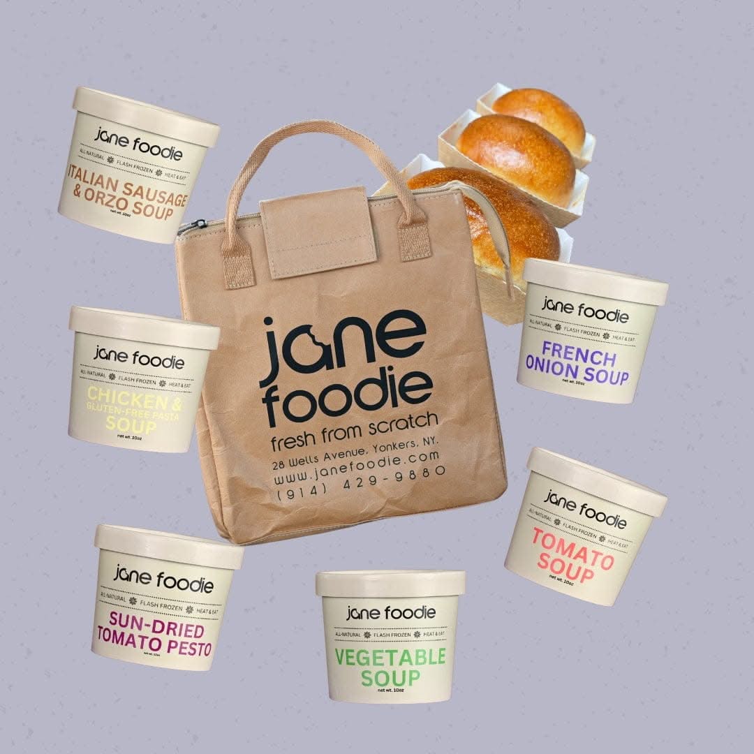 Jane Foodie Signature Soups Gift Tote with seven soup containers, insulated tote bag, and mini white bread loaves on lavender background.