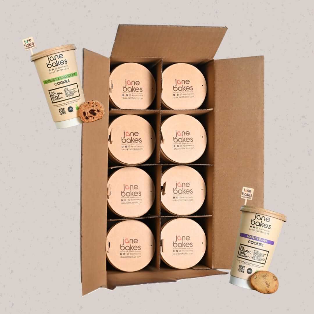 Open box of Jane Bakes Cookie Kraft Cups with two cookie tubs and cookies showcasing "Build Your Own Cookie Case" option.